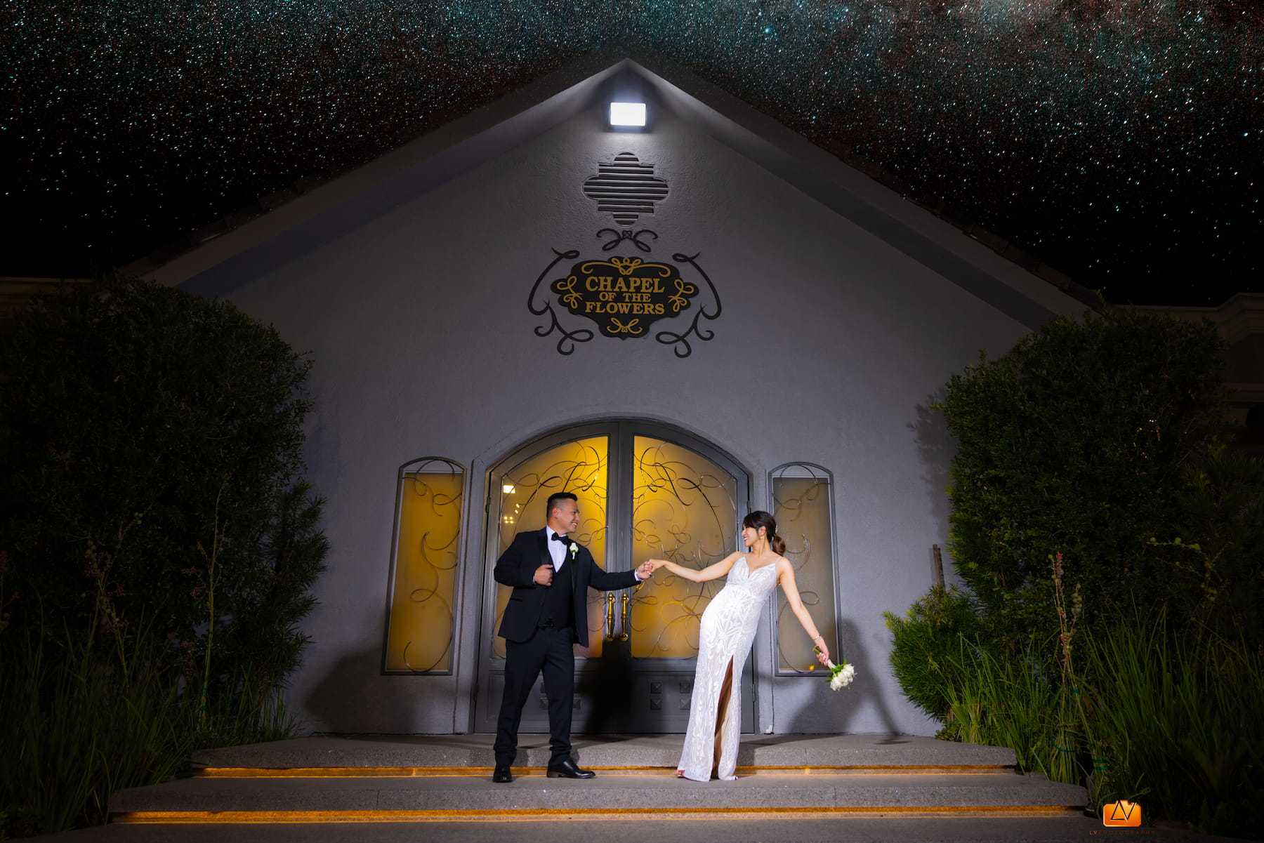 Bride and groom holding hands outside Chapel of the Flowers in Las Vegas at night under a starry sky