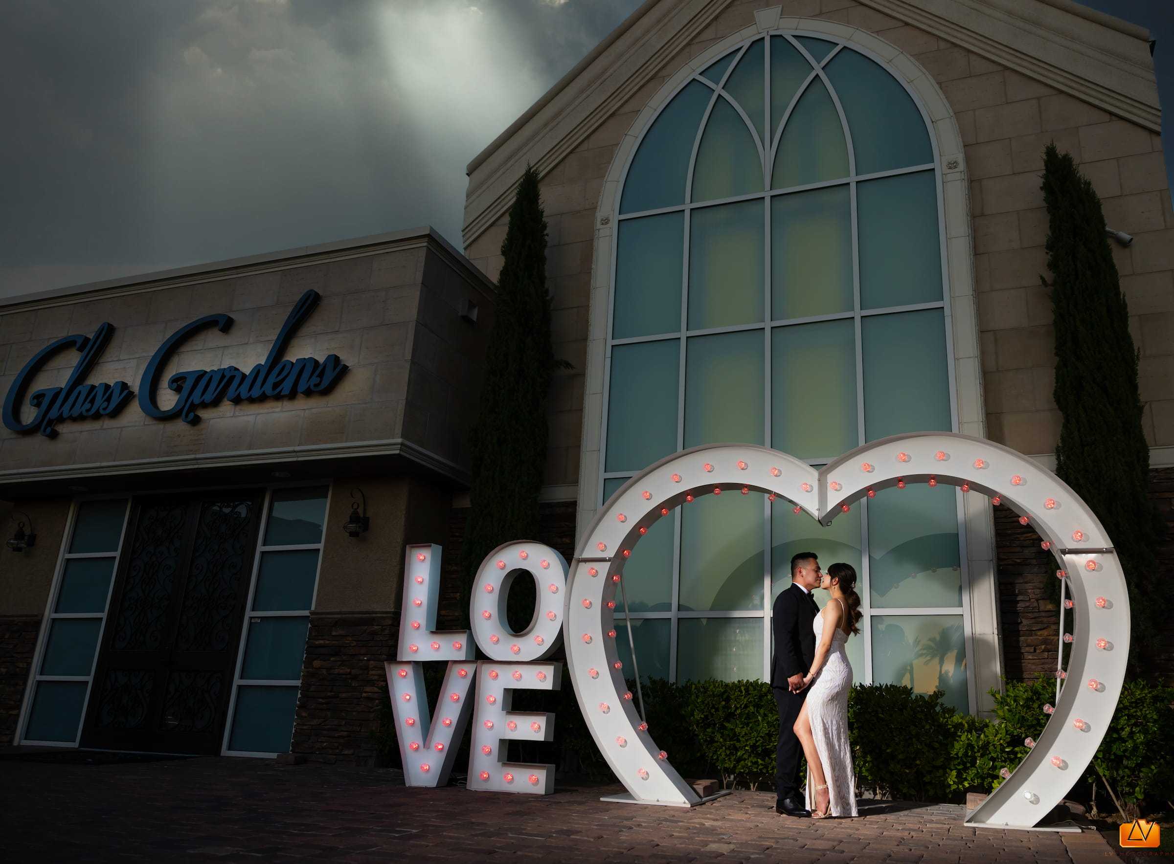 Bride and groom kissing in front of the LOVE sign at Chapel of the Flowers in Las Vegas