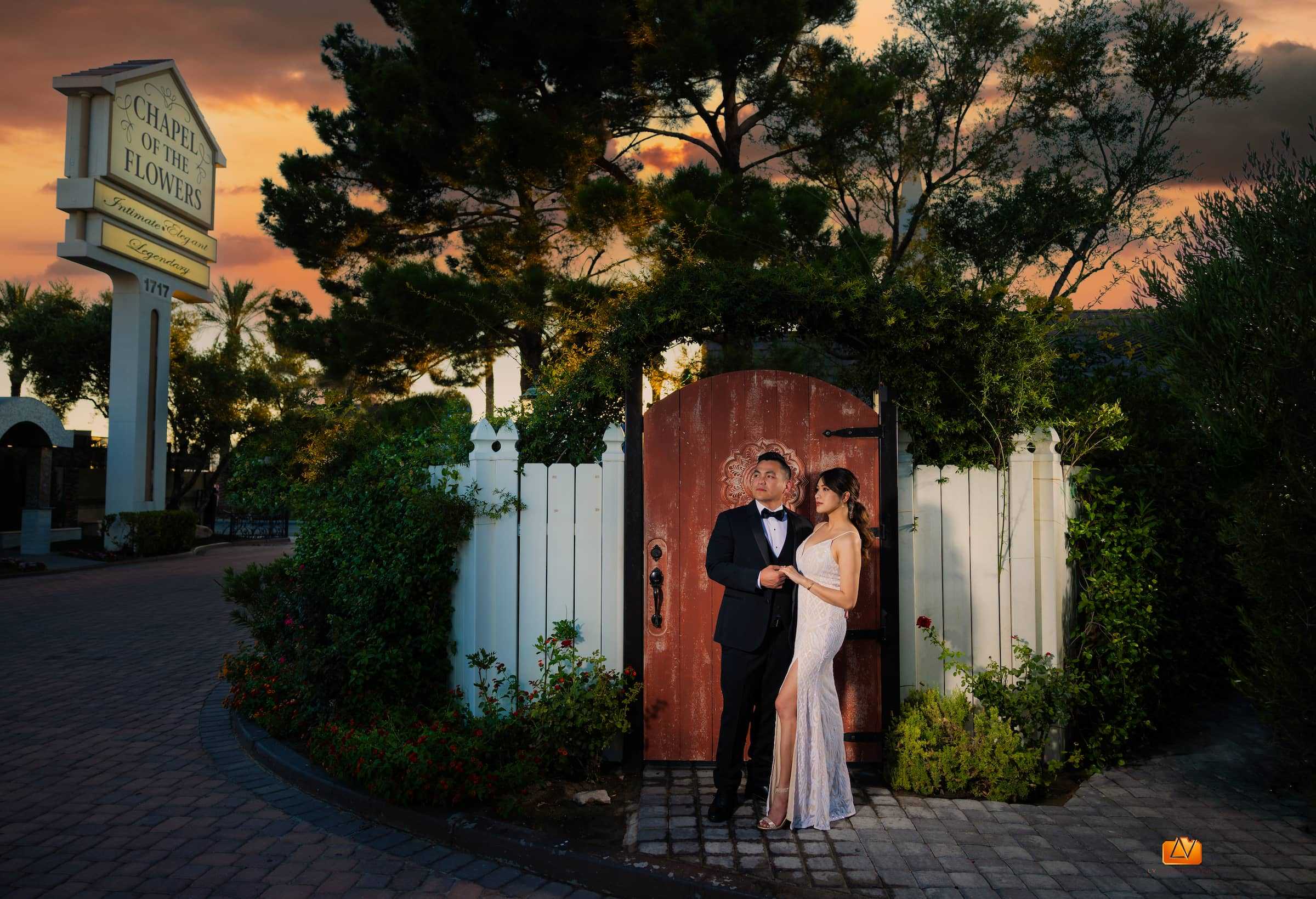 Bride and groom posing by the garden gate at Chapel of the Flowers in Las Vegas during sunset