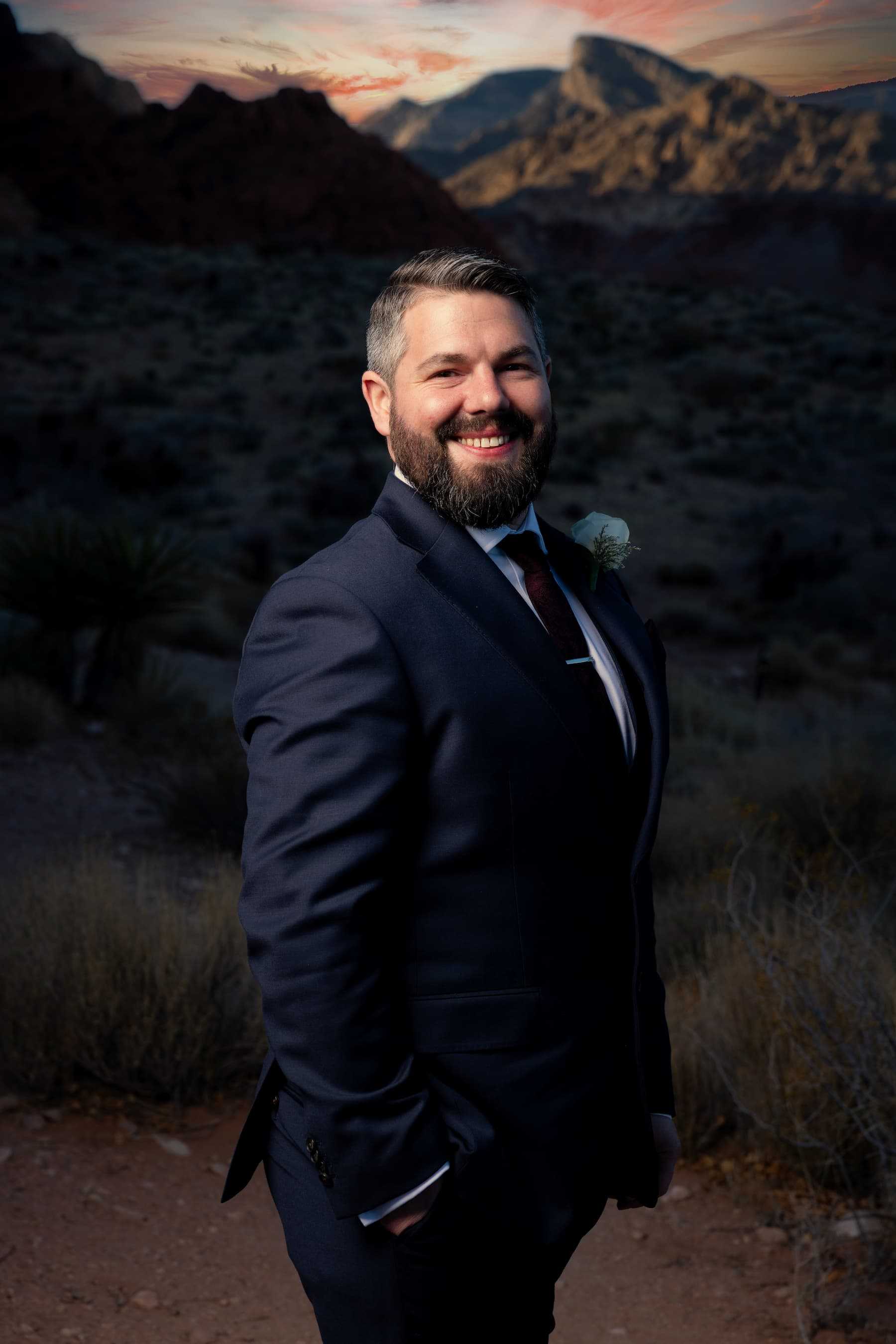 Groom smiling in a navy suit during a sunset portrait near Red Spring at Red Rock Canyon