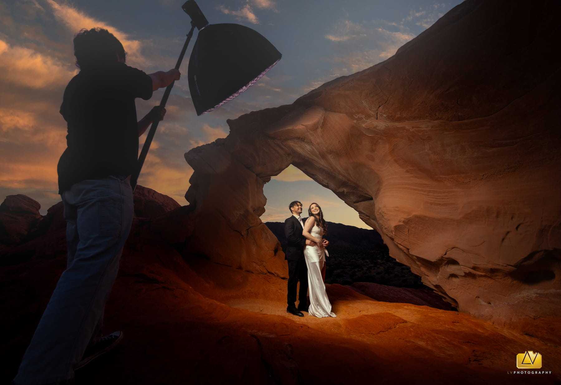 Behind the scenes wedding photography setup with bride and groom under a red sandstone arch at Valley of Fire near Las Vegas