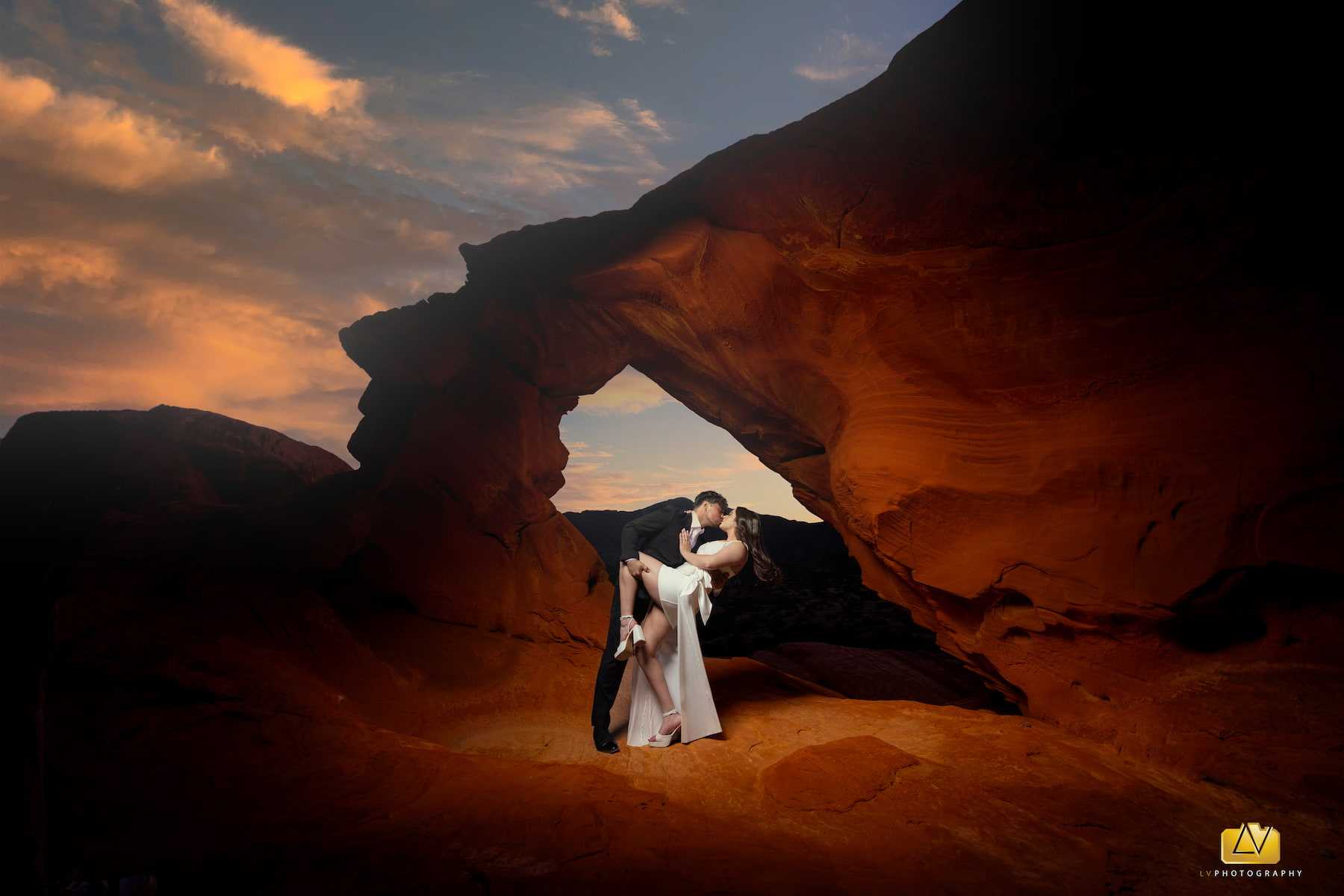 Bride and groom kissing beneath a red sandstone arch at Valley of Fire near Las Vegas